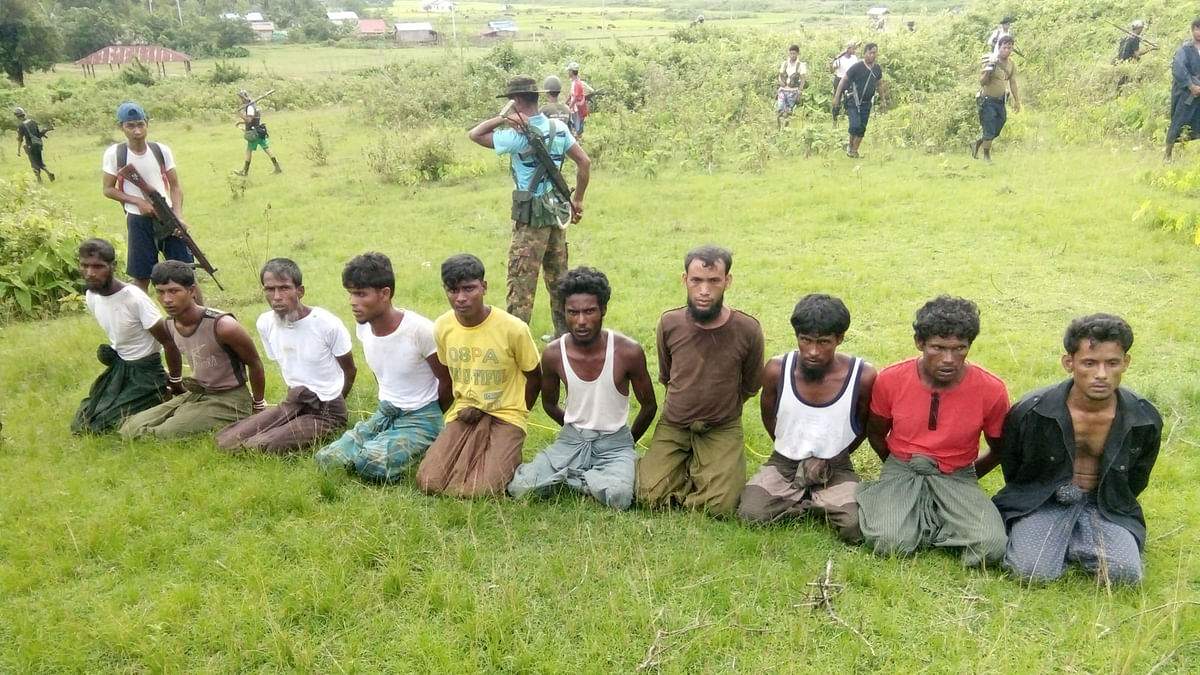 Ten Rohingya Muslim men with their hands bound kneel as members of the Myanmar security forces stand guard in Inn Din village. Reuters