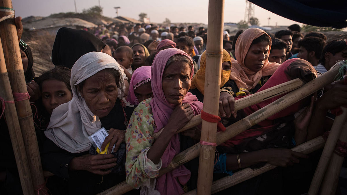 In this file photo taken on 28 November 2017, Rohingya Muslim refugees wait to be called to receive food aid of rice, water and cooking oil in a relief centre at the Kutupalong refugee camp in Cox`s Bazar. AFP