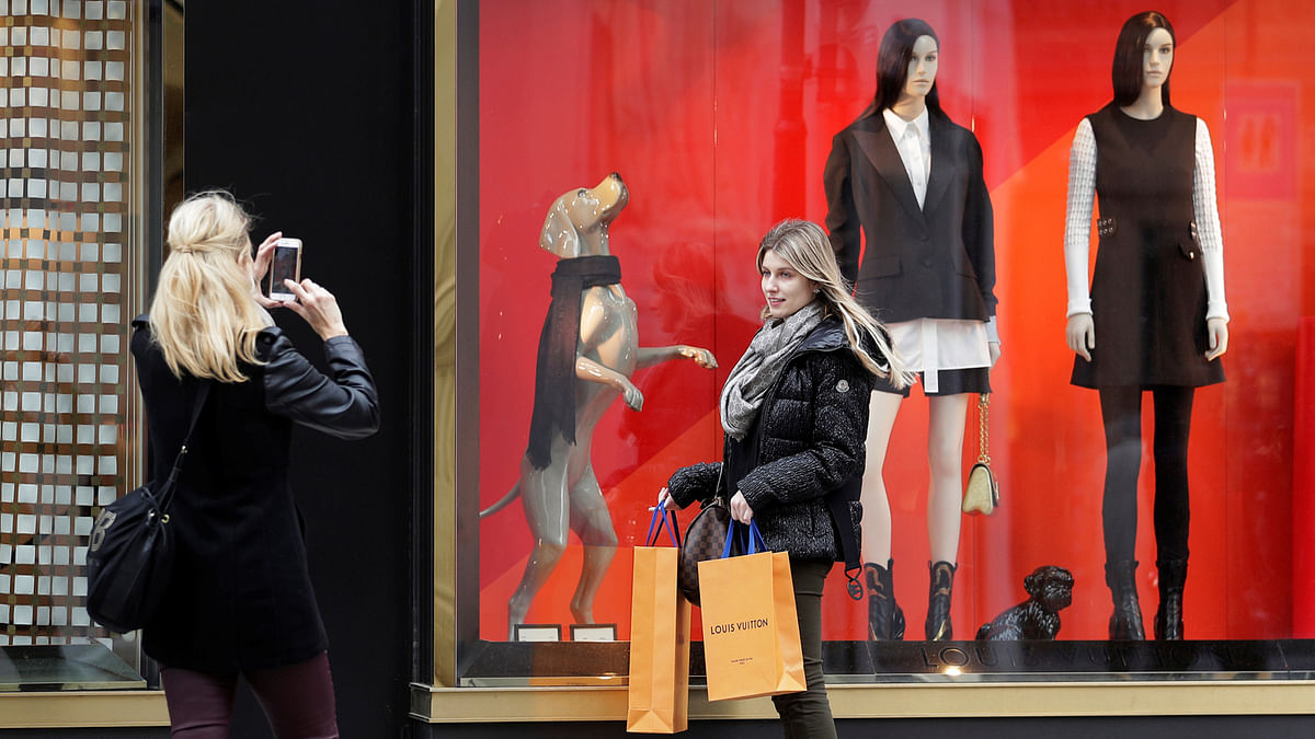 A woman poses in front of a Louis Vuitton store in the centre of Vienna, Austria on 12 March. Photo: Reuters