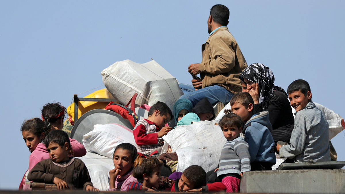 Children sit on a truck with their belongings in north-east Afrin, Syria on 13 March 2018. Photo: Reuters