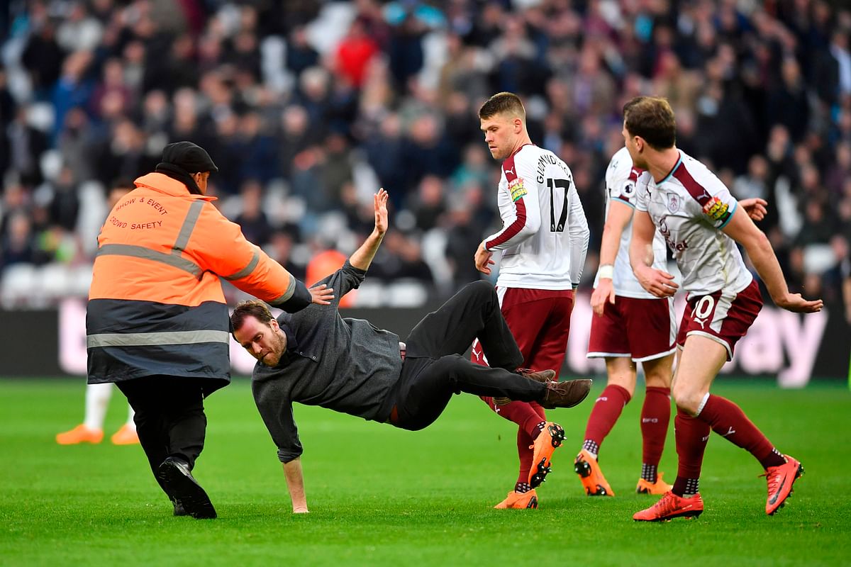 Burnley striker Ashley Barnes trips up a pitch invader during their English Premier League match against West Ham United at The London Stadium, in east London on March 10. AFP