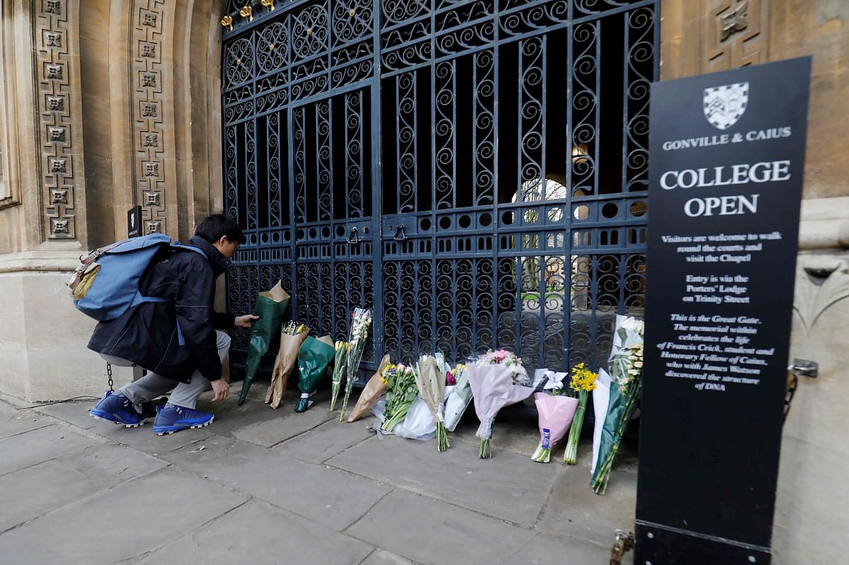 A man lays flowers outside Gonville and Caius College, at Cambridge University in Cambridge, on Wednesday following the death of British physicist, Stephen Hawking, who was a fellow of the University for over 50 years. Photo: AFP