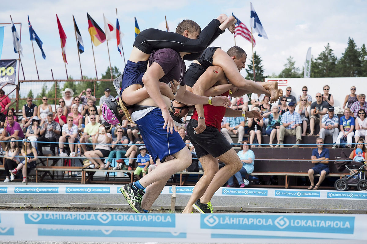 Tia Rope and Joonas Saukkonen (L) and Katja Hyvarinen and Jukka Podduikin, all of Finland, compete during the Wife Carrying World Championships in Sonkajarvi, Finland 2 July 2016. Reuters
