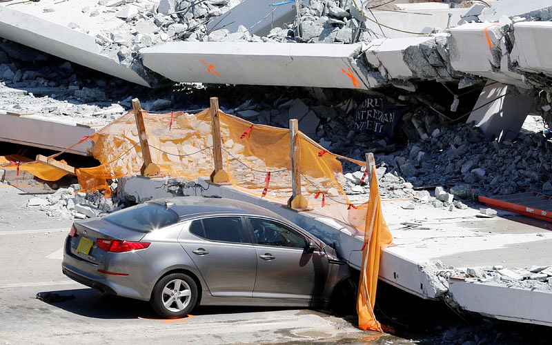 A damaged car is seen partially trapped as workers remove debris from a collapsed pedestrian bridge at Florida International University in Miami, Florida, US on 16 March 2018. Photo: Reuters