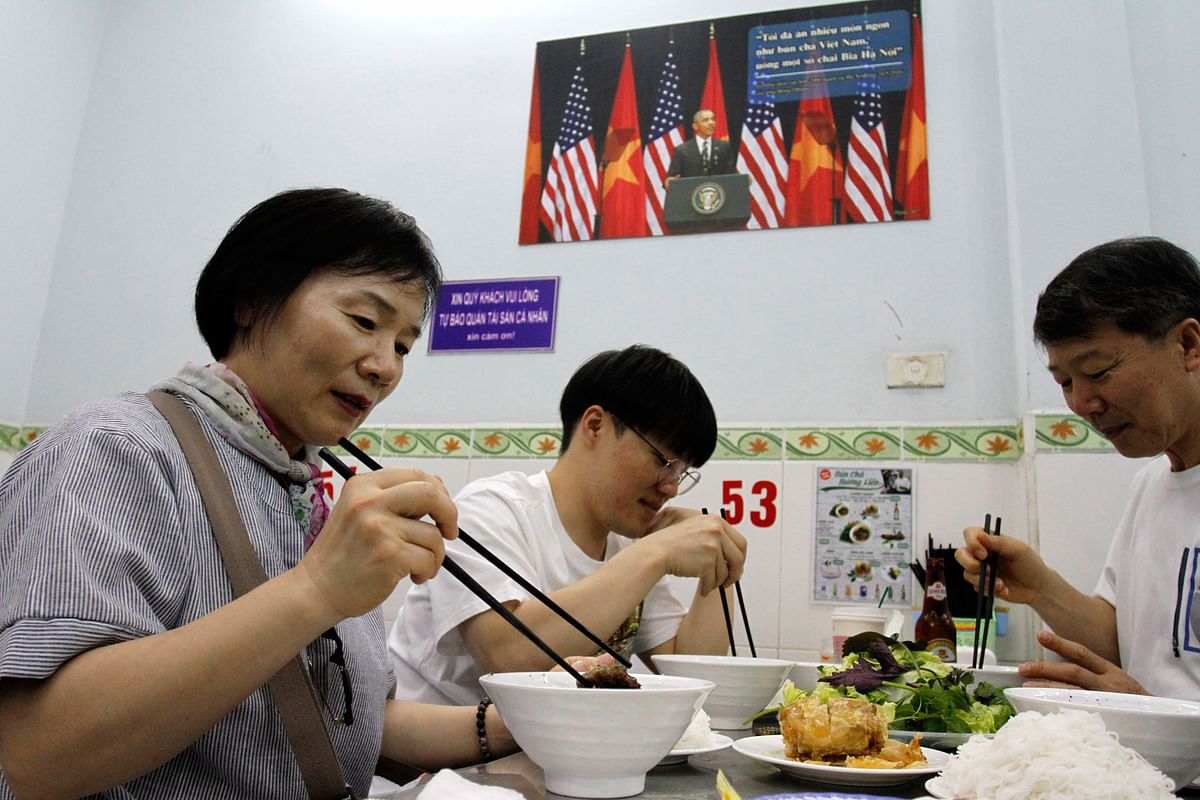 In this photograph taken on 20 March 2018, customers enjoy a meal at Bun Cha Huong Lien restaurant, now dubbed `bun cha Obama` with a photograph of former US President Barack Obama displayed on the wall, in Hanoi`s old quarter. Photo: AFP