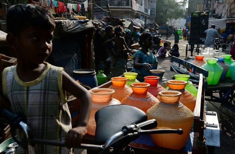 Indian residents carry plastic pots with drinking water in a supply cart from a government water supply tanker at their residential colony in Chennai. Photo: AFP