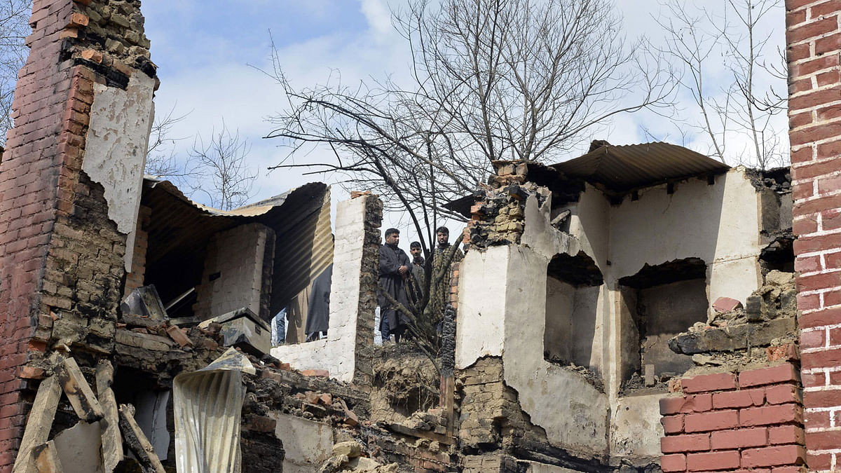 Indian Kashmiri villagers look on next to the debris of a house after a gunbattle between suspected militants and government forces in the Balhama area of Khanmoh district near Srinagar on 16 March 2018. AFP