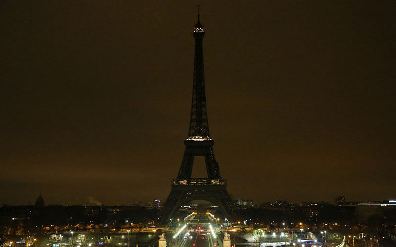 The lights of the Eiffel Tower are dimmed at midnight on Friday to honour victims killed at a supermarket in southwest France by a man claiming allegiance to the Islamic State. AFP