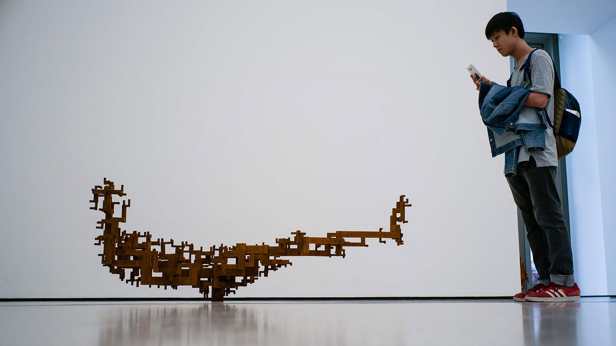 A visitor takes a photo of `Stem`, 2016, by British sculptor Antony Gormley, during the exhibition. AFP