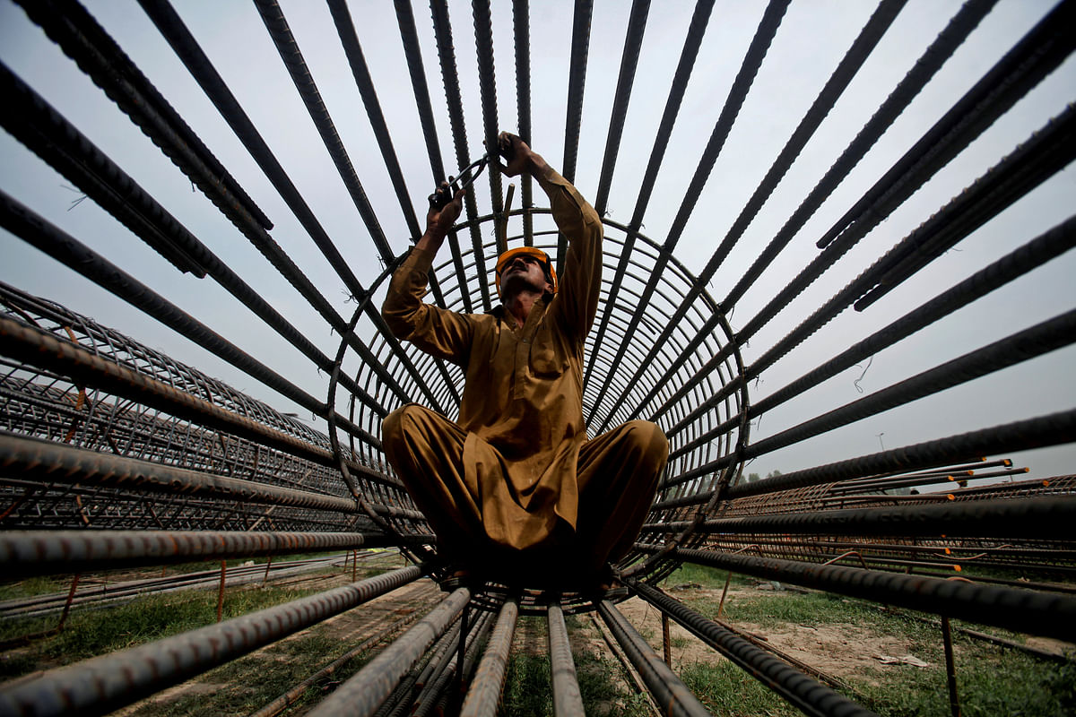 A worker ties steel bars at a construction site for a road in Peshawar, Pakistan, on 27 March 2018. Reuters