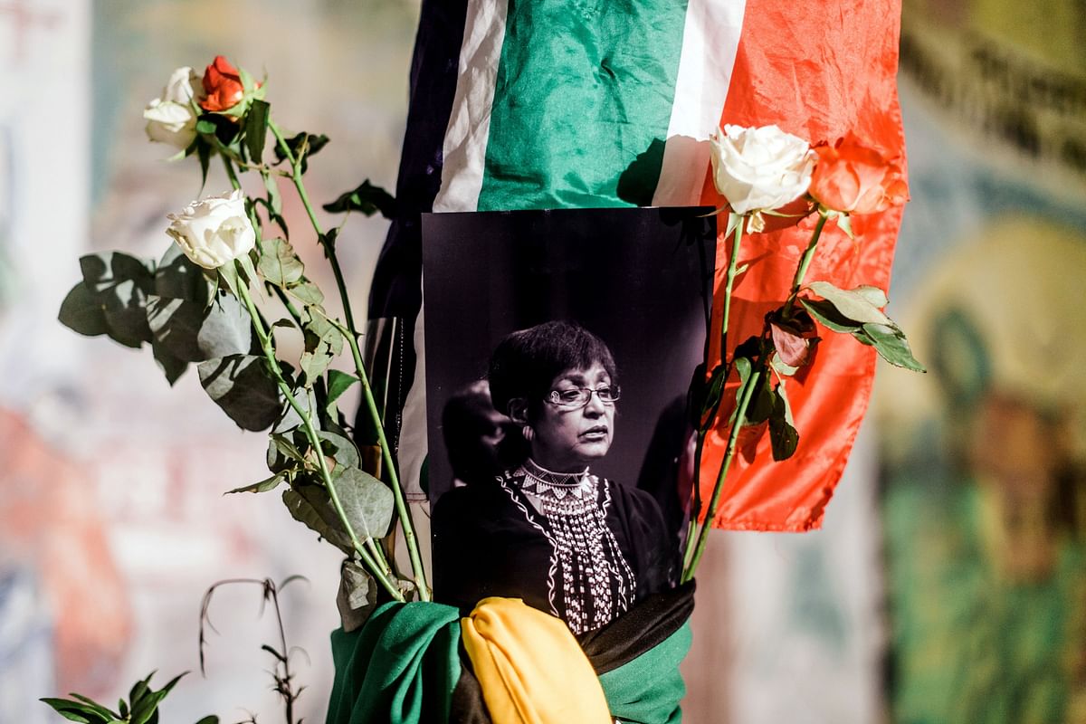 A black and white photograph of the late Winnie Madikizela-Mandela is surrounded by the South African and African National Congress (ANC) flags on a pole at the Old Durban Prison`s Human Rights wall as South Africans gather to pay respect to the late high-profile anti-apartheid activist during a candle vigil in Durban on 2 April 2018. Photo: AFP