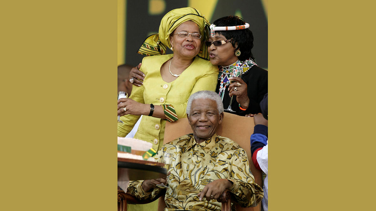Former South African president Nelson Mandela sits as Graca Macel and Winnie Madikizela Mandela, Mandela`s ex-wife, embrace each other during a rally, organised by the ANC to celebrate Mandela`s 90th birthday, at the Loftus stadium in Pretoria 2 August 2008. Reuters
