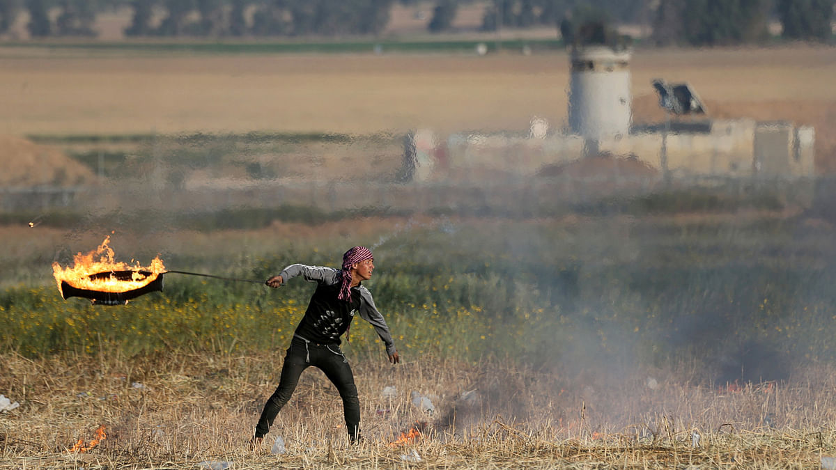 A Palestinian protester holds a burning tyre, during clashes with Israeli troops, at Israel-Gaza border in the southern Gaza Strip on 2 April. Photo: Reuters