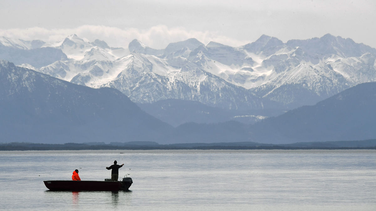 Fishermen prepare their fisher net in front of the Alp Mountains at the lake Starnberger in southern Germany, during nice spring weather with temperatures by 15 degrees on 3 April. Photo: AFP
