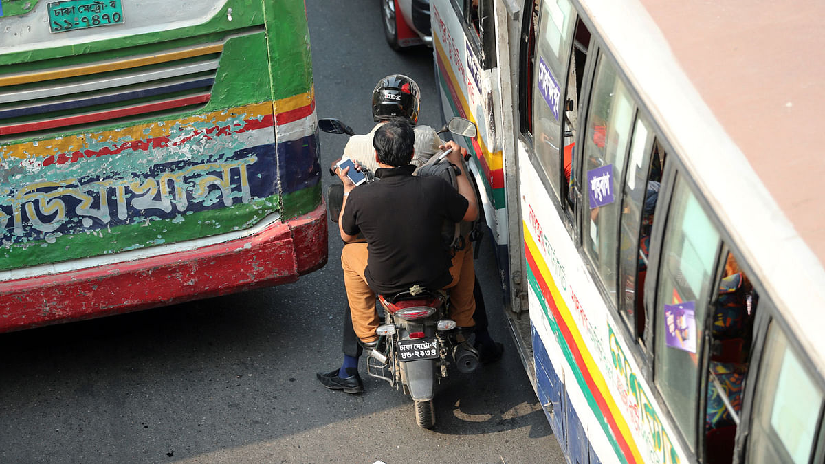 A motorbike driver tries to rush through the narrow gap between two buses near Shahbagh intersection in Dhaka on 5 April. Photo: Sajid Hossain