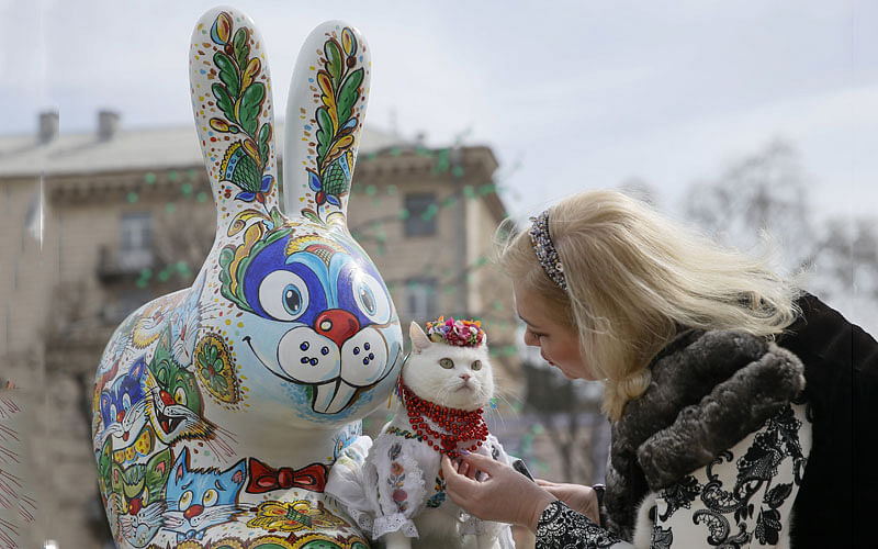 A woman dresses her cat before taking pictures near a painted Easter Bunny before the upcoming Orthodox Easter celebration, in central Kiev, Ukraine on 5 April. Photo: Reuters