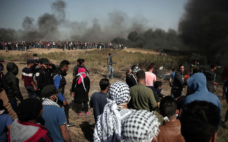 Palestinian protesters gathered as black smoke is seen from burning tires during a protest at the Gaza Strip`s border with Israel on 6 April. Photo: AP