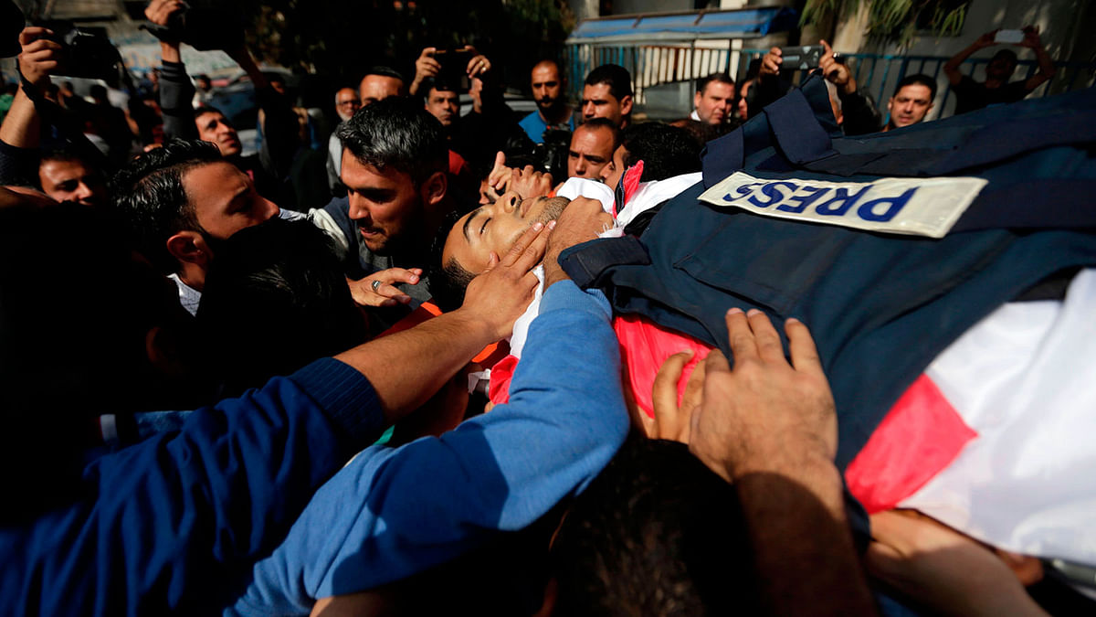 Mourners and journalists carry the body of Palestinian journalist Yasser Murtaja, during his funeral in Gaza City on 7 April, 2018. Photo: AFP