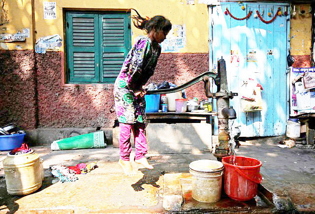 A girl uses a hand-pump to collect drinking water at a makeshift shelter in Kolkata, India, April 12, 2018. Photo : Reuters