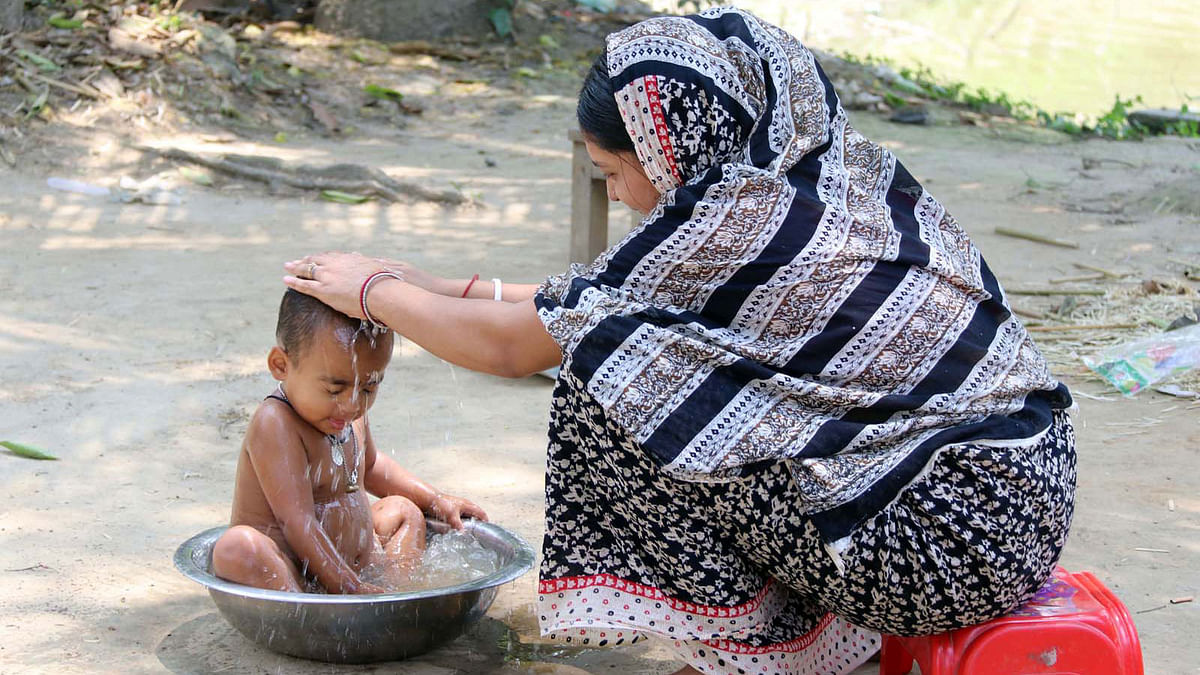 A woman bathes her baby in Baishnabpara of Cumilla on 12 April. Photo: Emdadul Haque