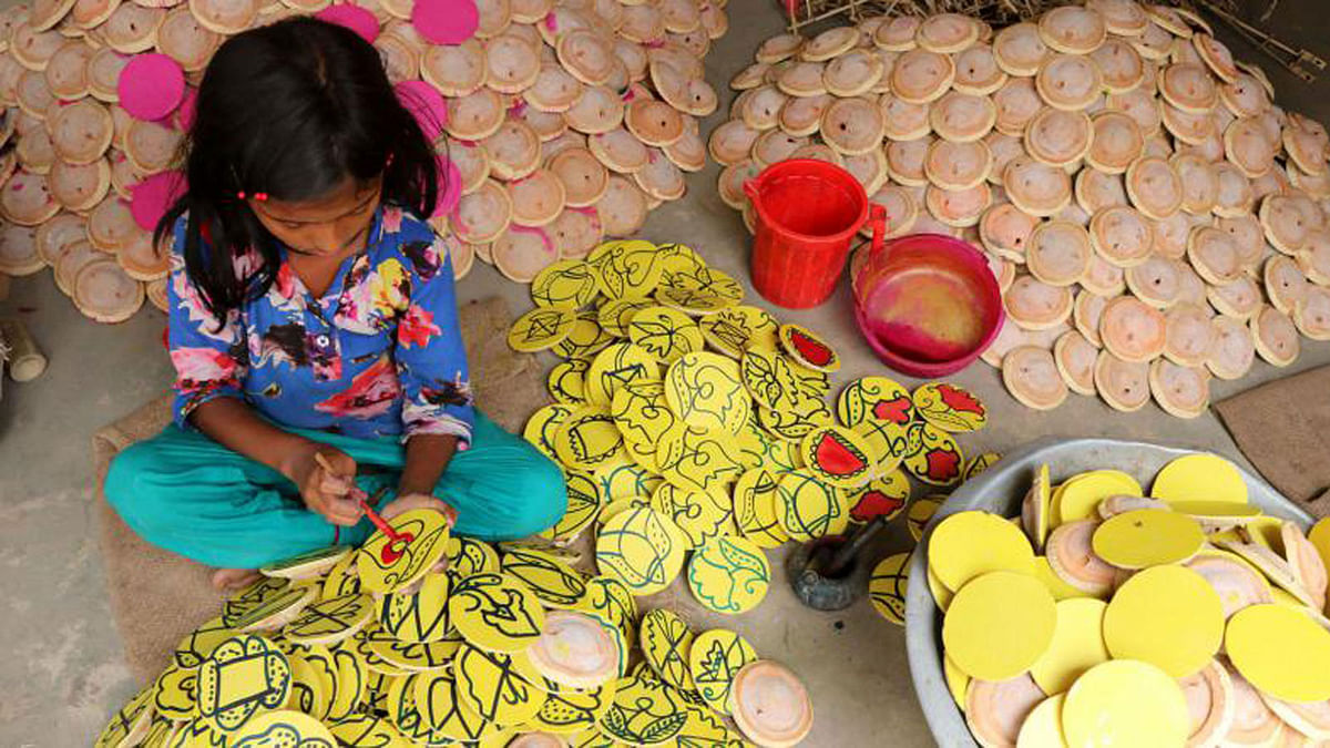 A girl busy in colouring the Tomtom cart (a toy) made of wood, bamboo and paper in the village of Kholash, Dupchachia upazila of Bagura. Photo: Soel Rana