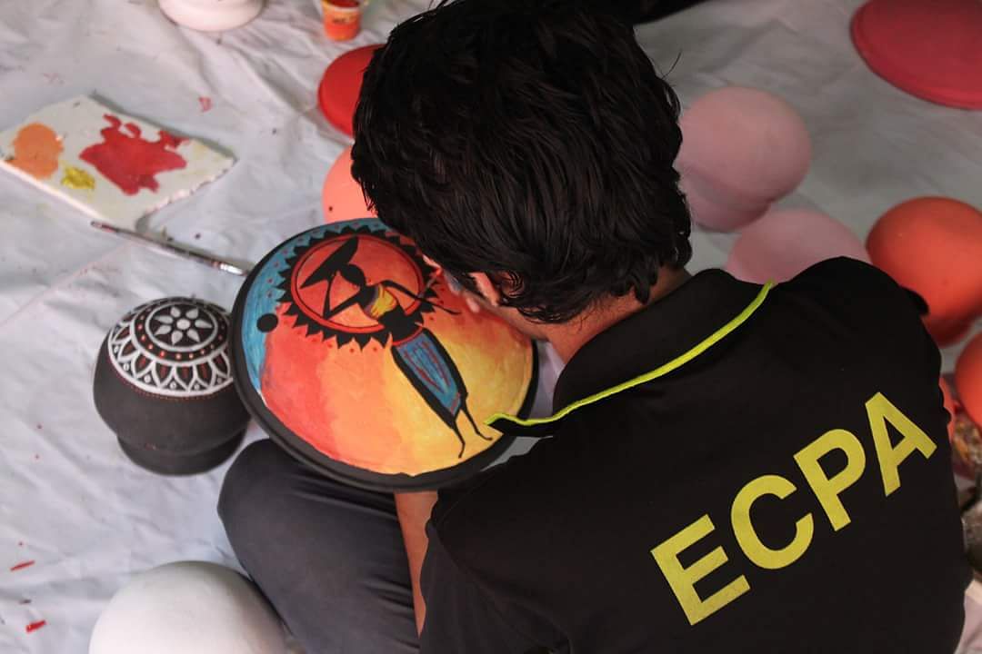 A student of East West University paints on a clay pot. Photo: Collected