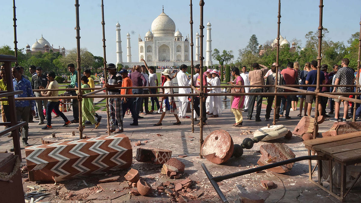 People gather around base of the Royal Gate entrance at the Taj Mahal complex next to a fallen minaret that collapsed during a storm in Agra on 12 April 2018. AFP