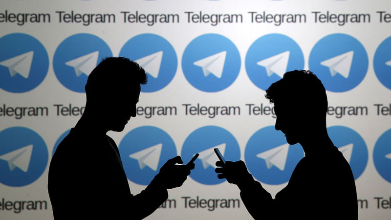 Two men pose with smartphones in front of a screen showing the Telegram logos in this picture illustration taken on 18 November 2015. Reuters File Photo