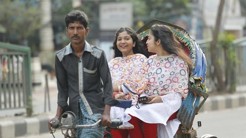 Two girls ride on a rickshaw to attend the Ramna Batamul Baishakh celebration in the early morning on 14 April. Photo: Sumon Yusuf