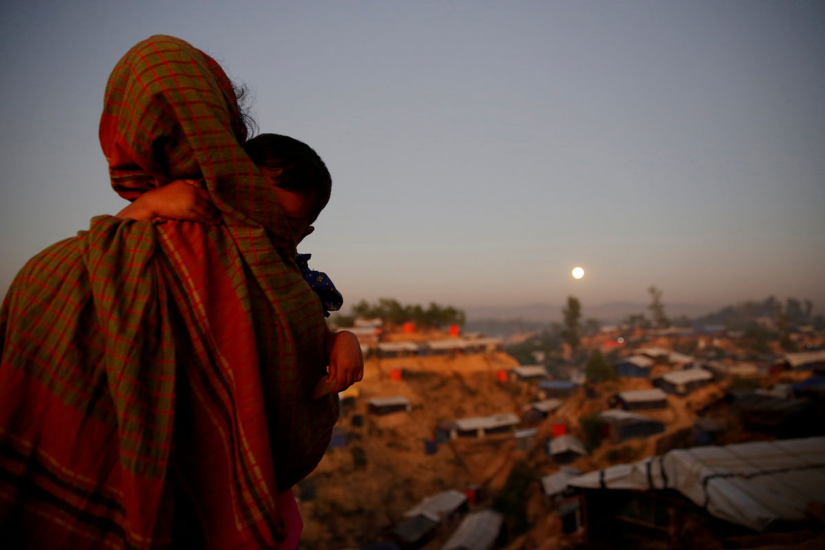 A Rohingya refugee looks at the full moon with a child in tow at Balukhali refugee camp near Cox’s Bazar. Reuters file photo