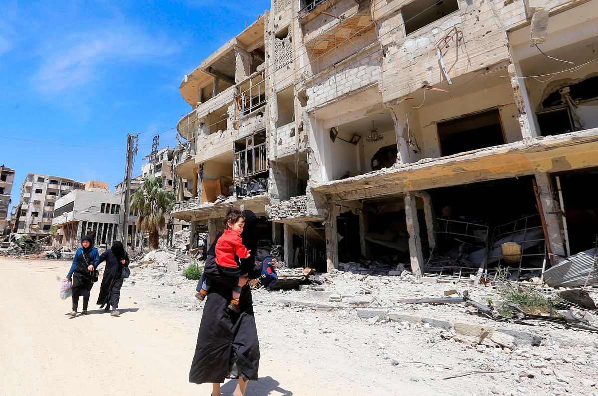 Syrians walk down the street past destroyed buildings in Douma on the outskirts of Damascus on Monday during an organised media tour after the Syrian army declared that all anti-regime forces have left Eastern Ghouta, following a blistering two month offensive on the rebel enclave. Photo: AFP