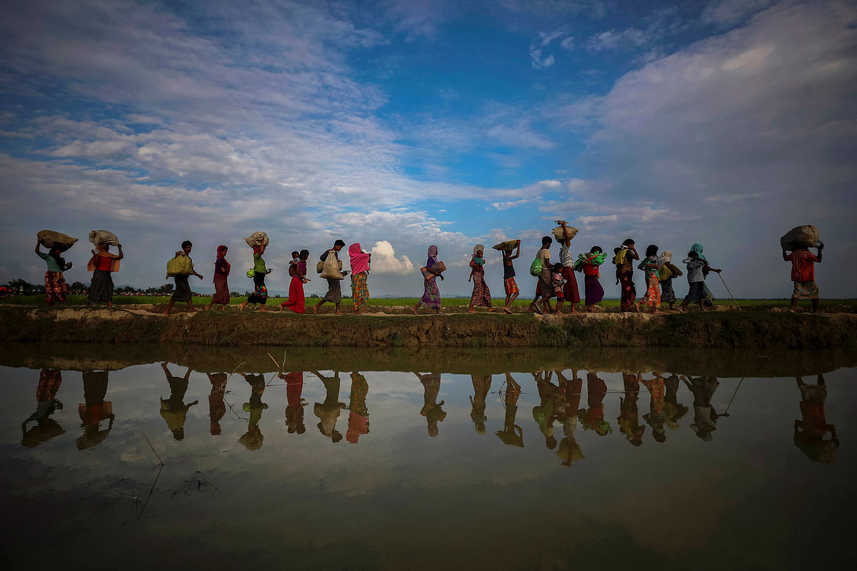 Rohingya refugees are reflected in rain water along an embankment next to paddy fields after fleeing from Myanmar into Palang Khali, near Cox’s Bazar, Bangladesh 2 November 2017. Photo: Reuters