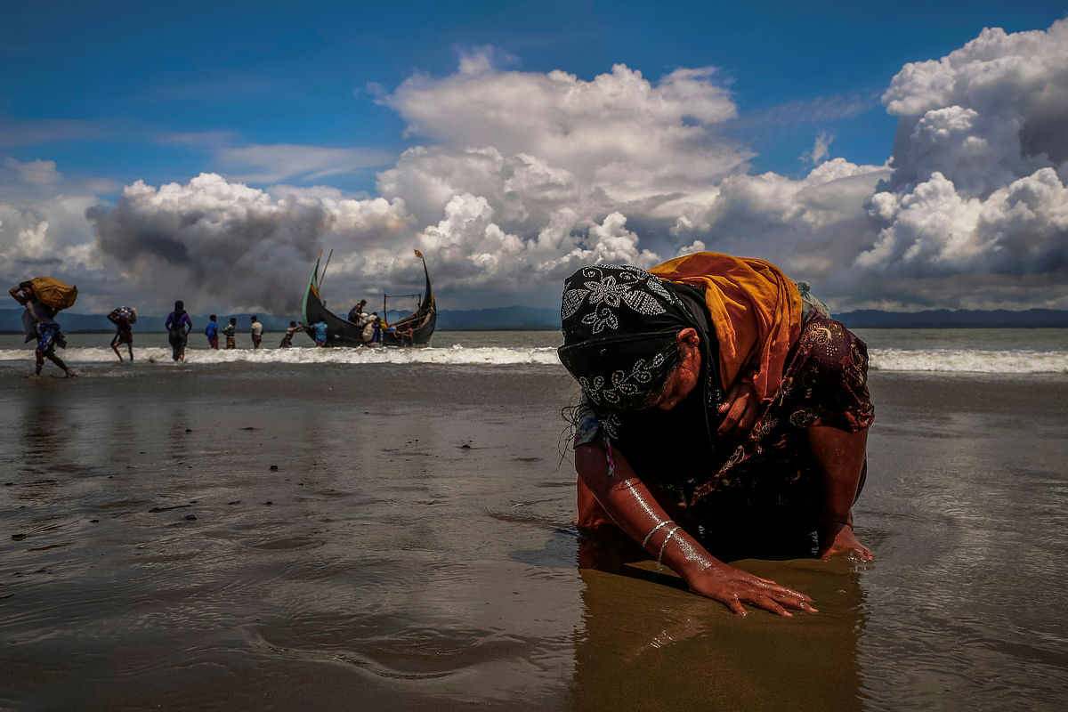 An exhausted Rohingya refugee woman touches the shore after crossing the Bangladesh-Myanmar border by boat through the Bay of Bengal, in Shah Porir Dwip, Bangladesh 11 September 2017. Photo: Reuters