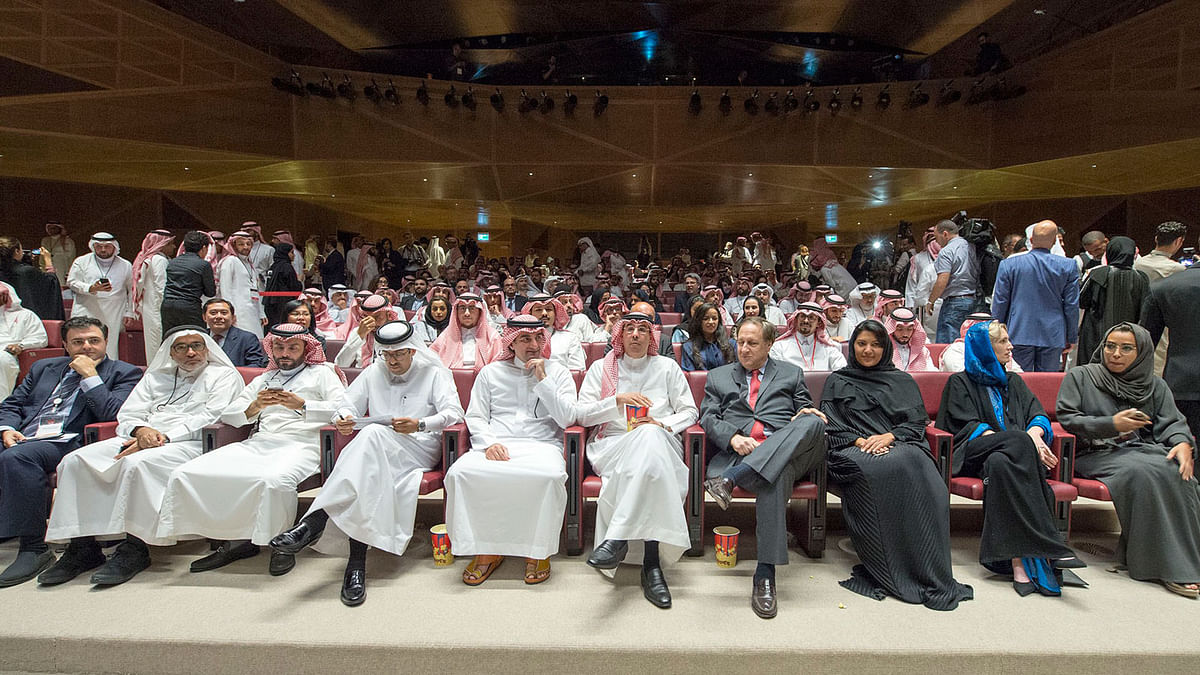 A handout picture provided by the Saudi Royal Palace on 18 April, 2018, shows Saudi Information Minister Awwad Alawwad (C) holding a small bucket of popcorn as he attends a test screening at the AMC cinema in the capital Riyadh, the first test in over three decades. Photo: AFP