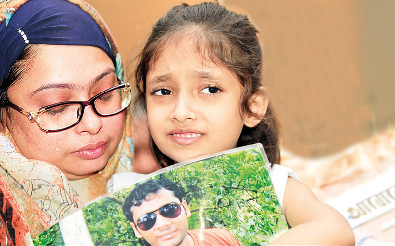 Parvez Hossain`s daughter Hridy holds up a picture of her missing father at a gathering held to demand the return of forced disapperance victims