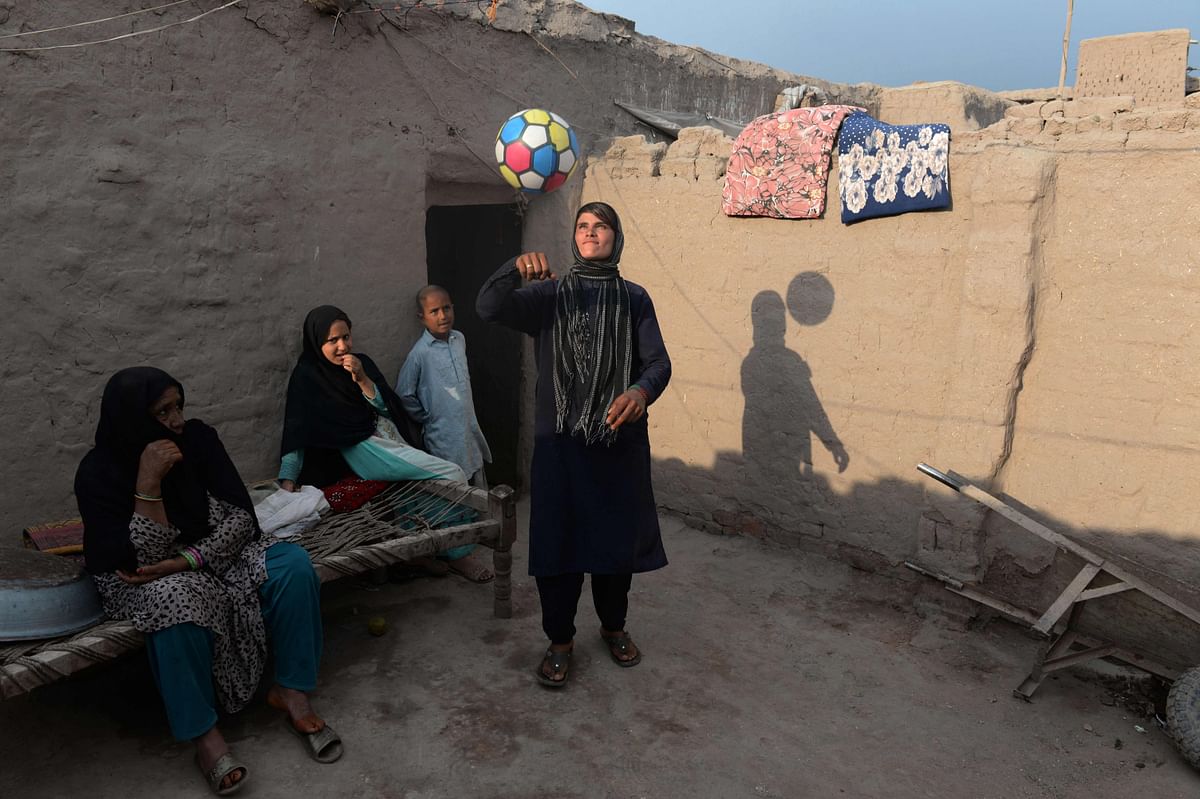 This photograph taken on 20 March, 2018 shows Afghan female labourer Sitara Wafadar (R), 18, who dresses as a male in order to support her family, playing with a ball at her home in Sultanpur village in Surkh Rod district, in Afghanistan`s eastern Nangarhar province. Photo: AFP