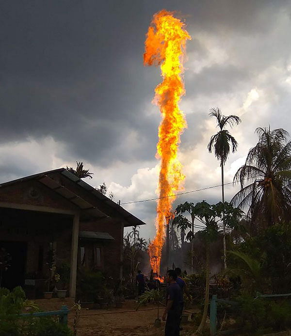 People try to extinguish a fire at an oil well in Peureulak, Indonesia`s Aceh province on 25 April. Photo: AFP