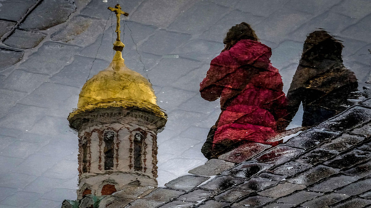 Women are reflected in a puddle as they walk across Red Square in Moscow on 26 April. Photo: AFP