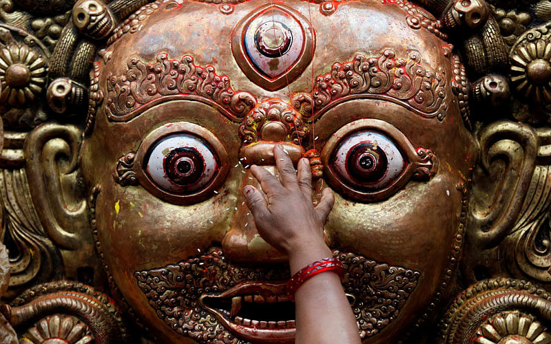 A hand of a devotee is pictured as she sprinkles rice grains while offering prayer on the mask of Bhairab, which is kept on the chariot of Rato Machhindranath, during the chariot festival in Lalitpur, Nepal on 27 April. Photo: Reuters
