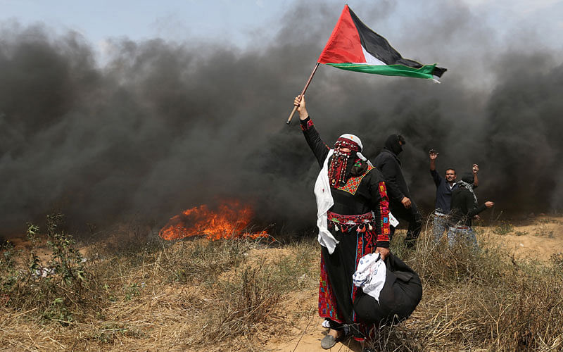 A woman demonstrator holds a Palestinian flag during clashes with Israeli troops at a protest where Palestinians demand the right to return to their homeland, at the Israel-Gaza border in the southern Gaza Strip on 27 April. Photo: Reuters