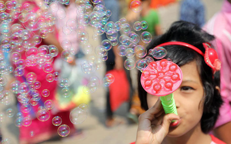 A girl makes soap-bubble while visiting Baisakhi fair in Chattogram on 27 April. Photo: Jewel Shil