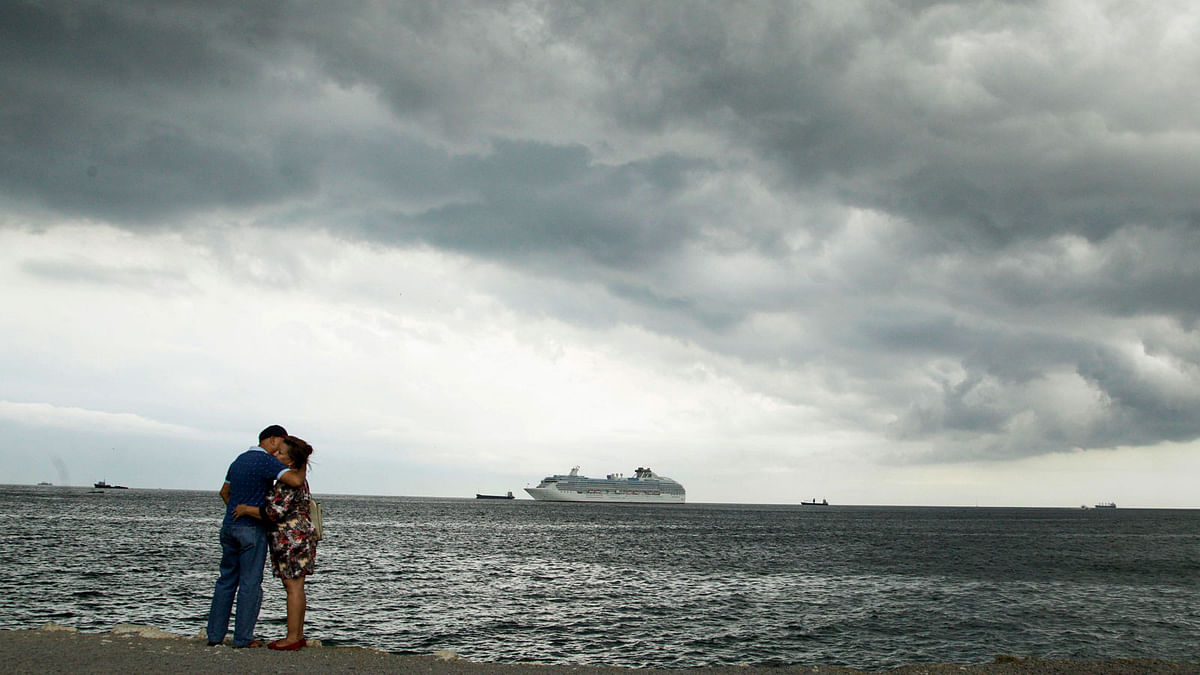 A couple embraces under cloudy skies along the shore of Panama Bay where a cruise ship is anchored, in Panama City on 26 April. Photo: AP