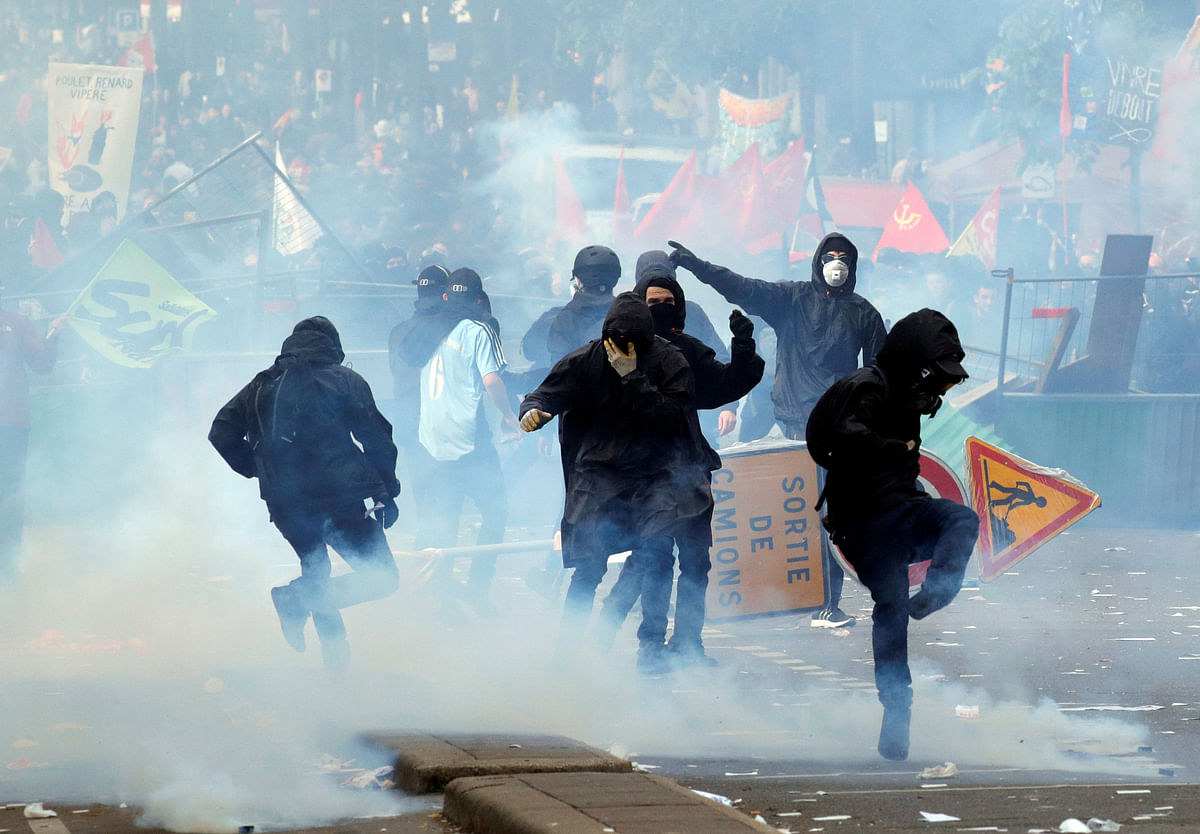 Tear gas floats around masked protesters during clashes with French CRS riot police at the May Day labour union rally in Paris, France on 1  May. Photo: Reuters