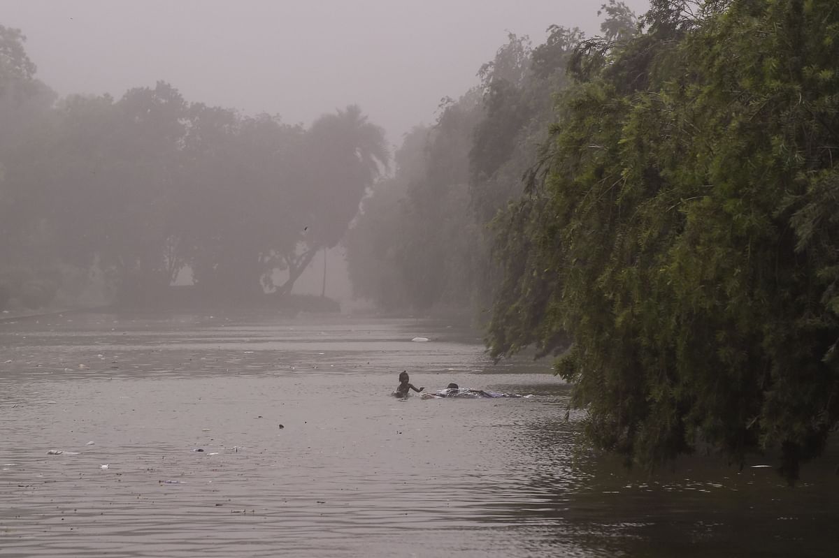 Indian children swim in a pond during a dust storm in New Delhi on 2 May, 2018. Photo: AFP