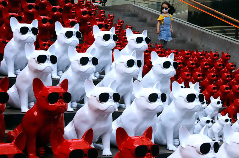 A child wearing a mask walks past audio speakers in the shape of dogs displayed at a shopping district in Beijing, China on 3 May. Photo: AP