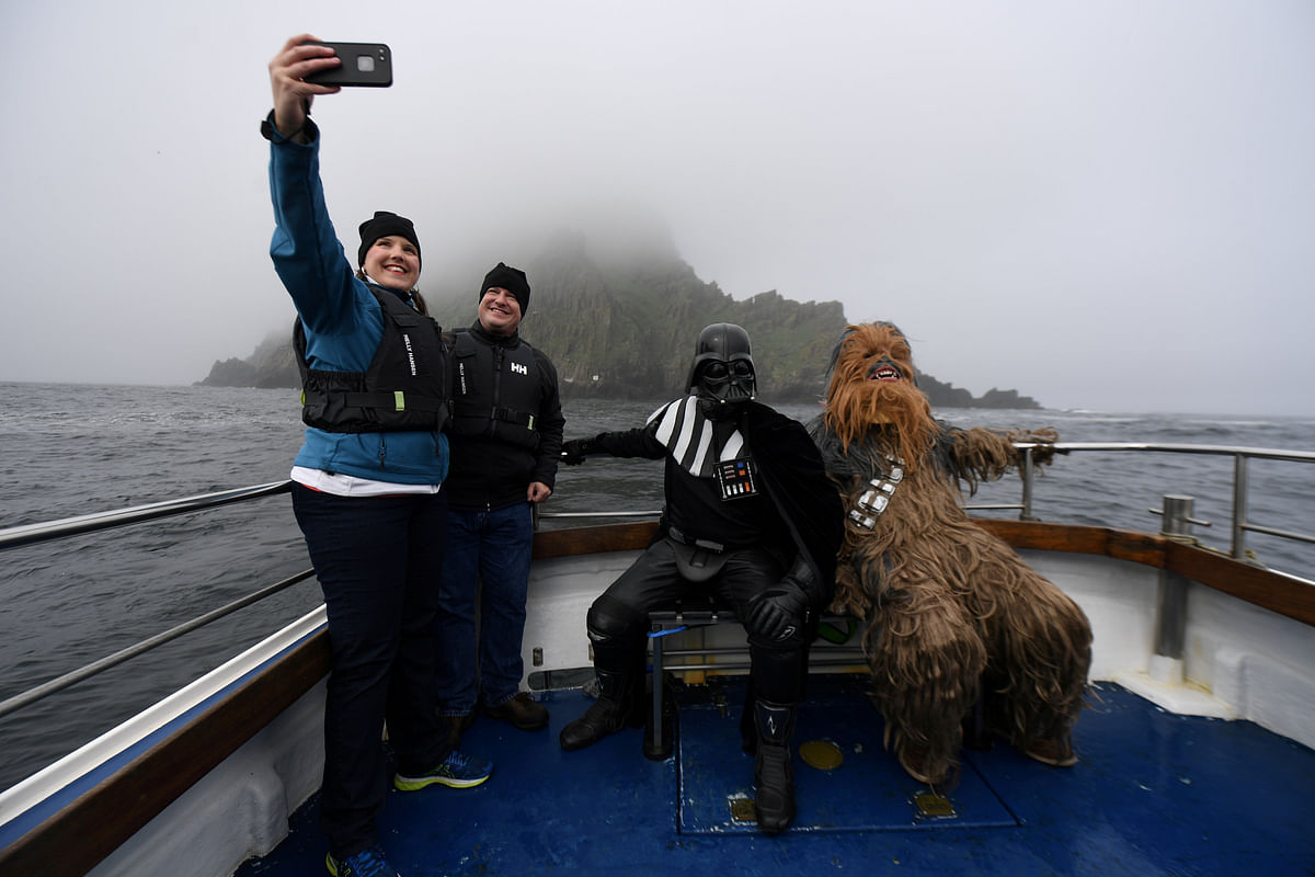 Holidaymakers take a selfie, along with Star Wars fans dressed in costume as Darth Vader and Chewbacca, on a boat trip to Skellig Island during the inaugural `May The 4th Be With You` festival in the County Kerry village of Portmagee, Ireland on 4 May 2018. Photo: AFP