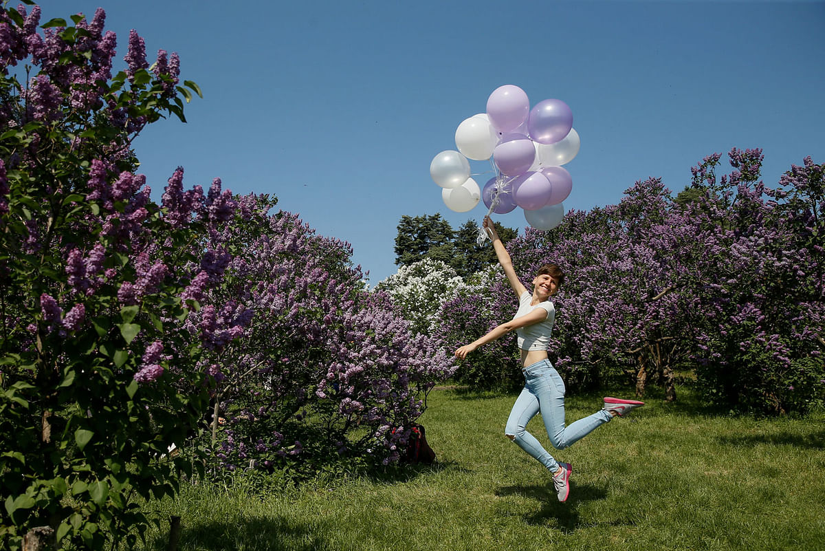 A woman jumps with balloons while she poses for a picture at a park in Kiev, Ukraine on 6 May. Photo: Reuters