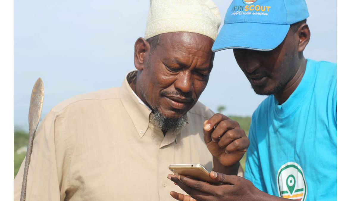 Herder Buchu Boru (L) and Abdikadir Halkane (R), an Afriscout marketer, look at the Afriscout phone application in Arkamana village, Marsabit County, Kenya, April 11, 2018. Photo : Thomson Reuters Foundation
