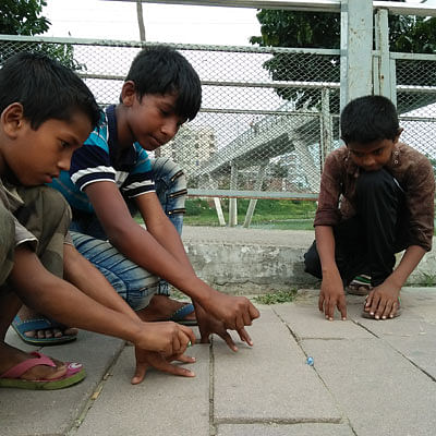 Children playing with small marbles on the footpath of Hatirjheel, Dhaka. A recent photo by Nusrat Nowrin