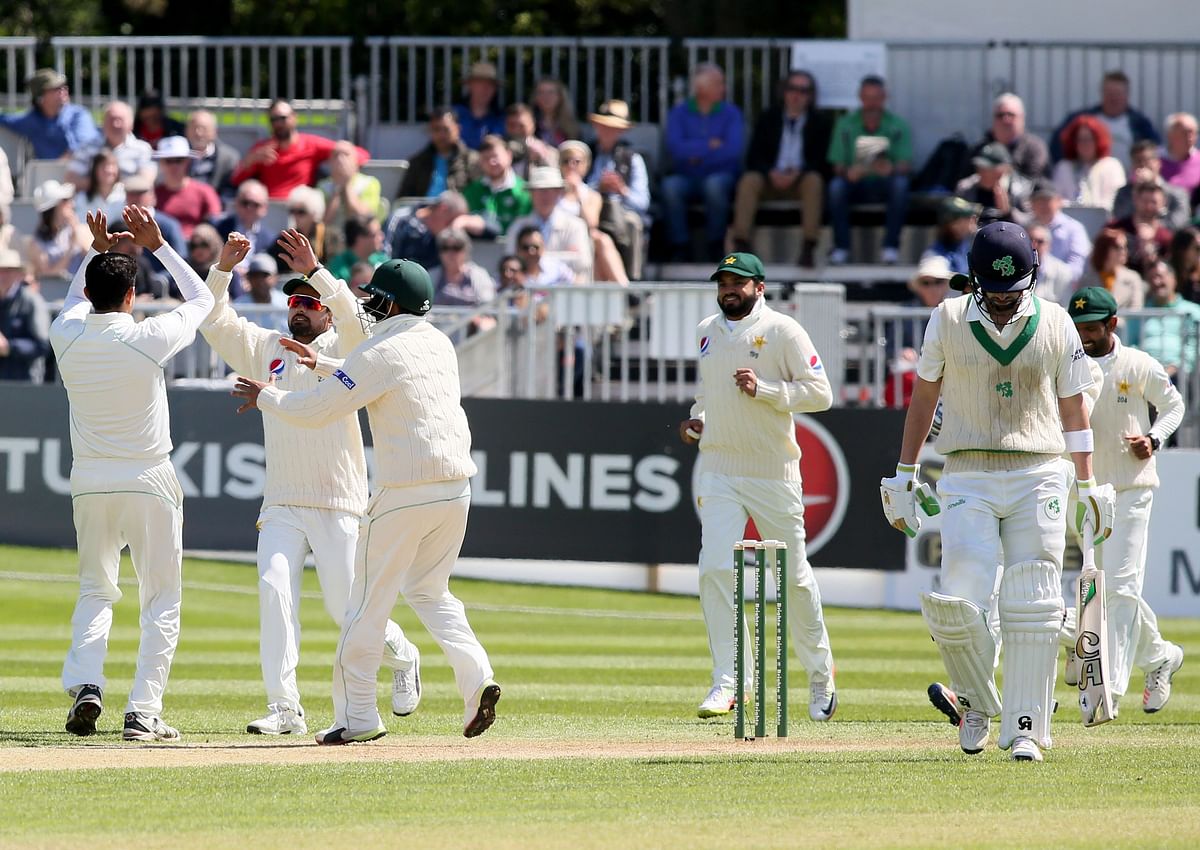 Pakistan players celebrate taking the wicket of Ireland`s Andrew Balbirnie (R) during play on day three of Ireland`s inaugural test match against Pakistan at Malahide cricket club, in Dublin on 13 May. Photo: AFP